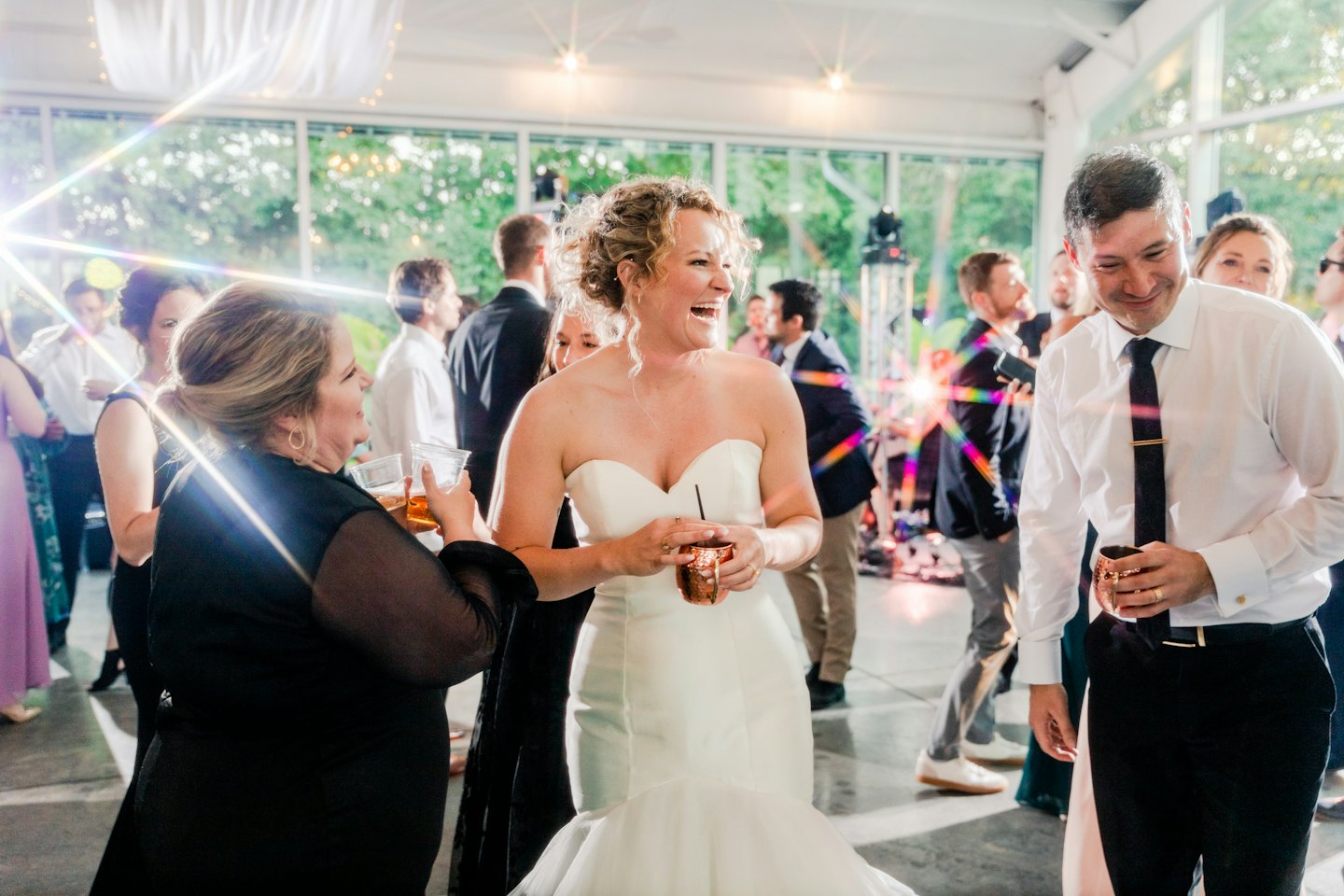 Bride laughing with guests at a wedding reception.