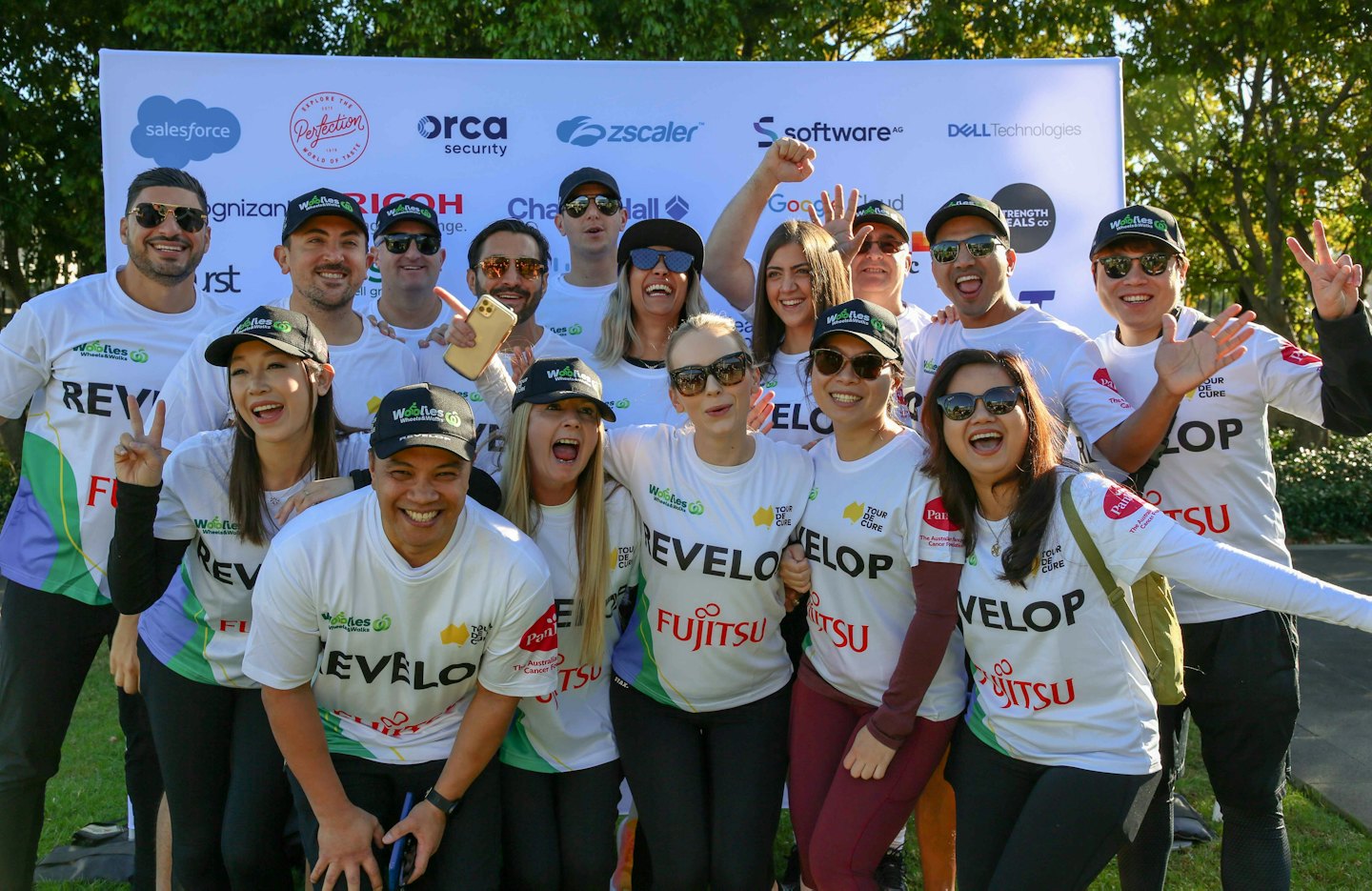A group of colleagues in branded t-shirts standing together outdoors.